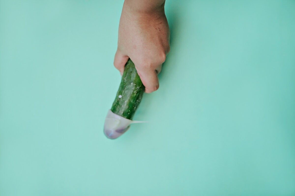 A Person Holding Green Cucumber on Teal Table