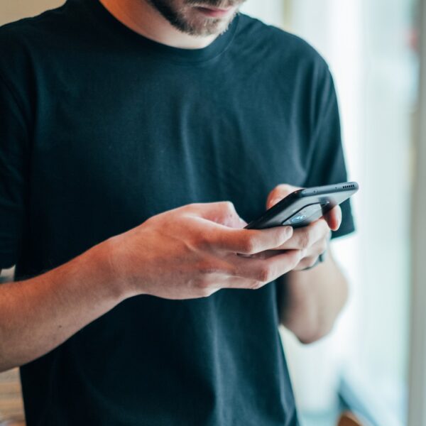 man in black crew-neck top using smartphone