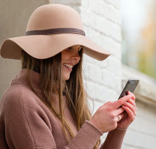 woman in brown hat and brown sweater holding smartphone