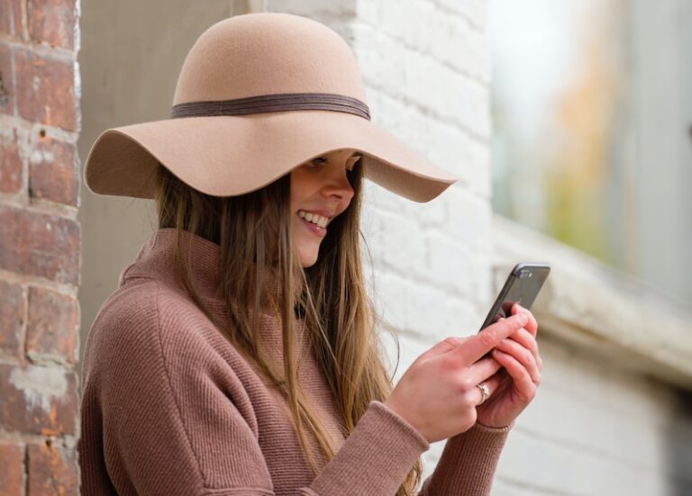 woman in brown hat and brown sweater holding smartphone