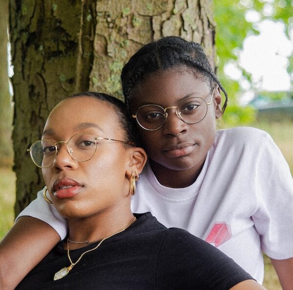 woman in black t-shirt wearing eyeglasses sitting with woman in white t-shirt wearing eyeglasses