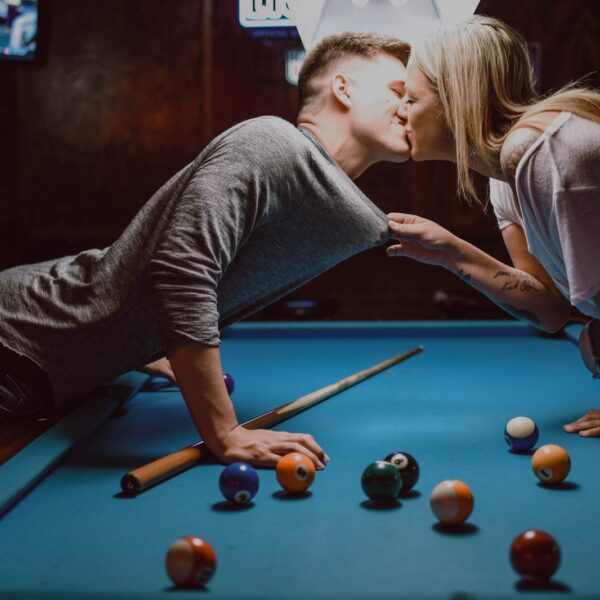 man and woman kissing on pool table