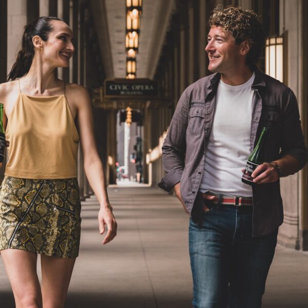 man in white tank top and black jacket standing beside woman in white tank top