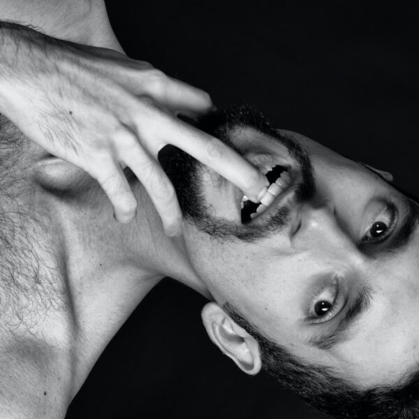 grayscale photography of man biting his finger