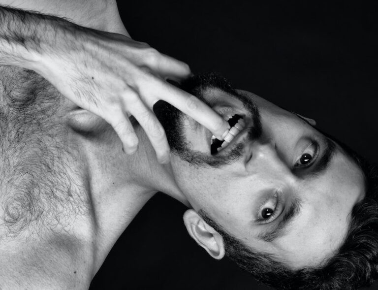 grayscale photography of man biting his finger