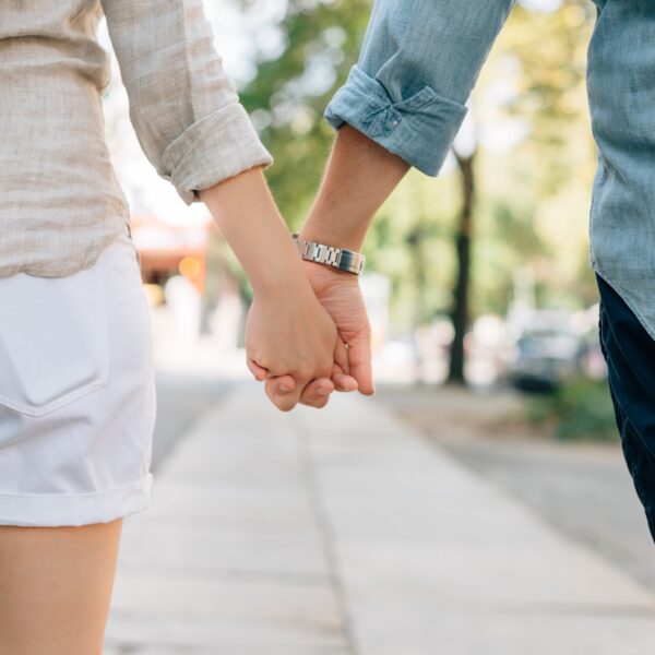 man and woman holding hands together in walkway during daytime