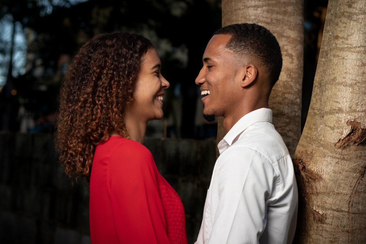 man in white dress shirt kissing woman in red dress